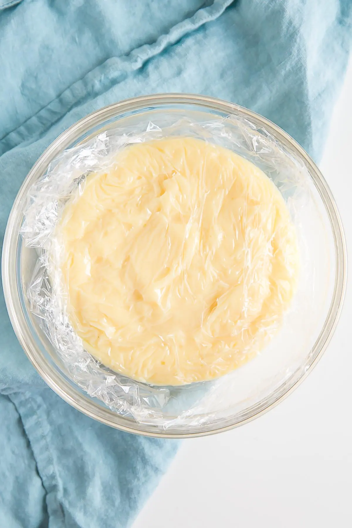 Creme Patissiere in a bowl with plastic wrap directly on top.