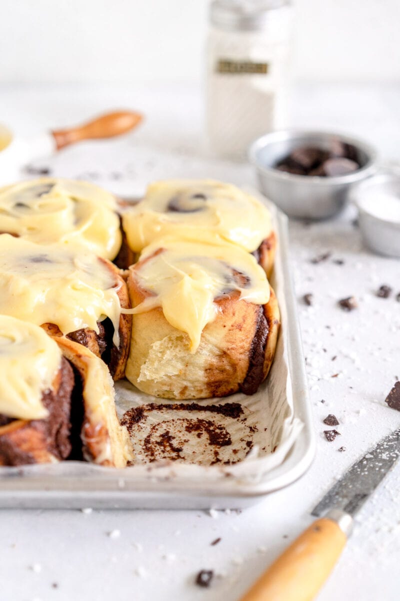 side shot of baked sweet rolls with orange cream cheese icing