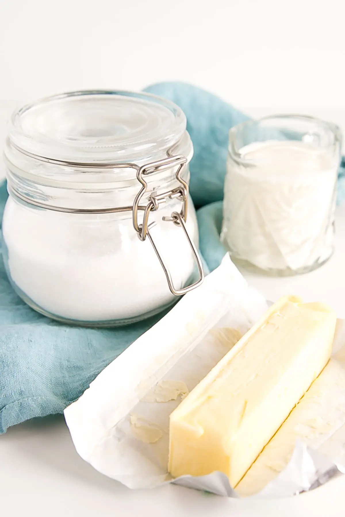 Ingredients -- cream, sugar, butter, on a blue cloth.