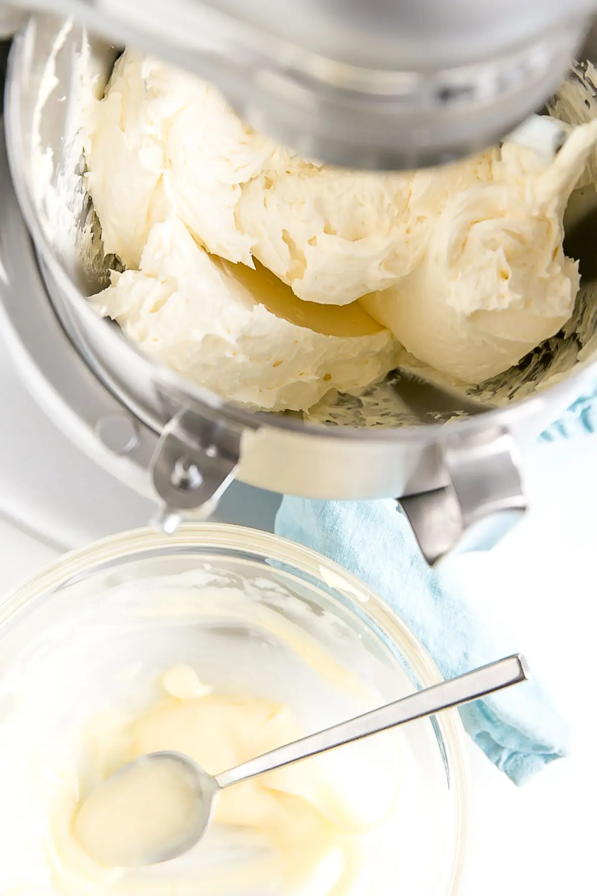 Mixer with bowl of pastry cream and spoon next to it.