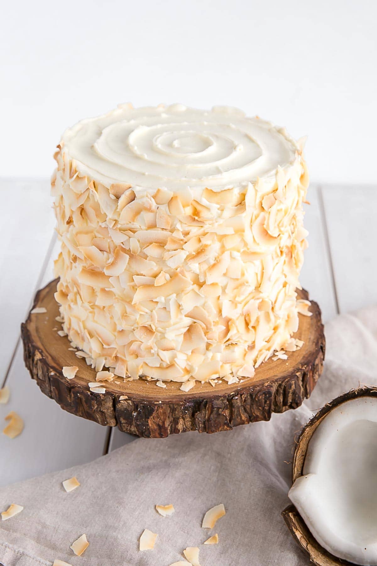 Homemade coconut cake decorated with toasted coconut and a swirl of frosting on the top.