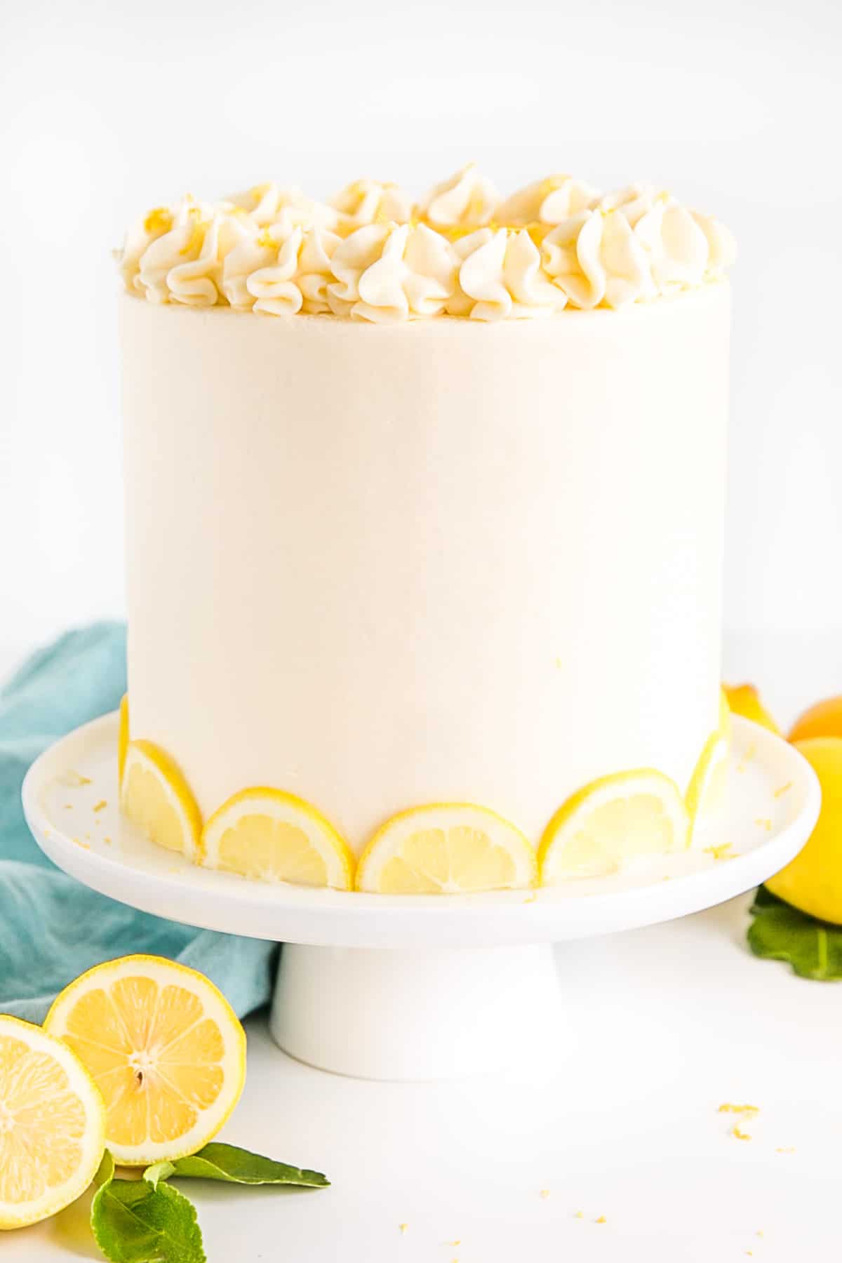 Cake on a cake stand with a blue cloth behind it.